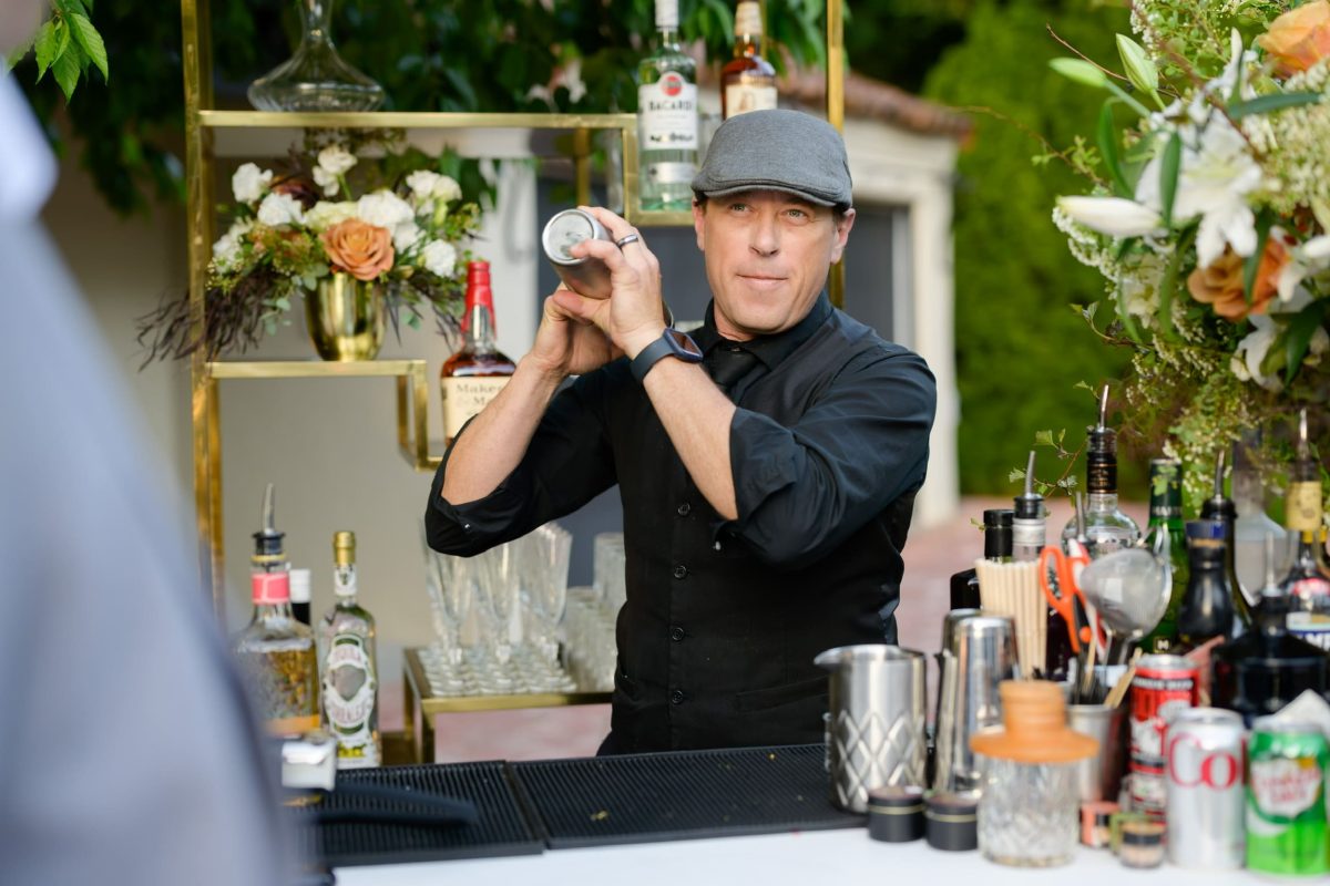 PSRT bartender shaking drink at a Bay Area catering event with live paella station in background