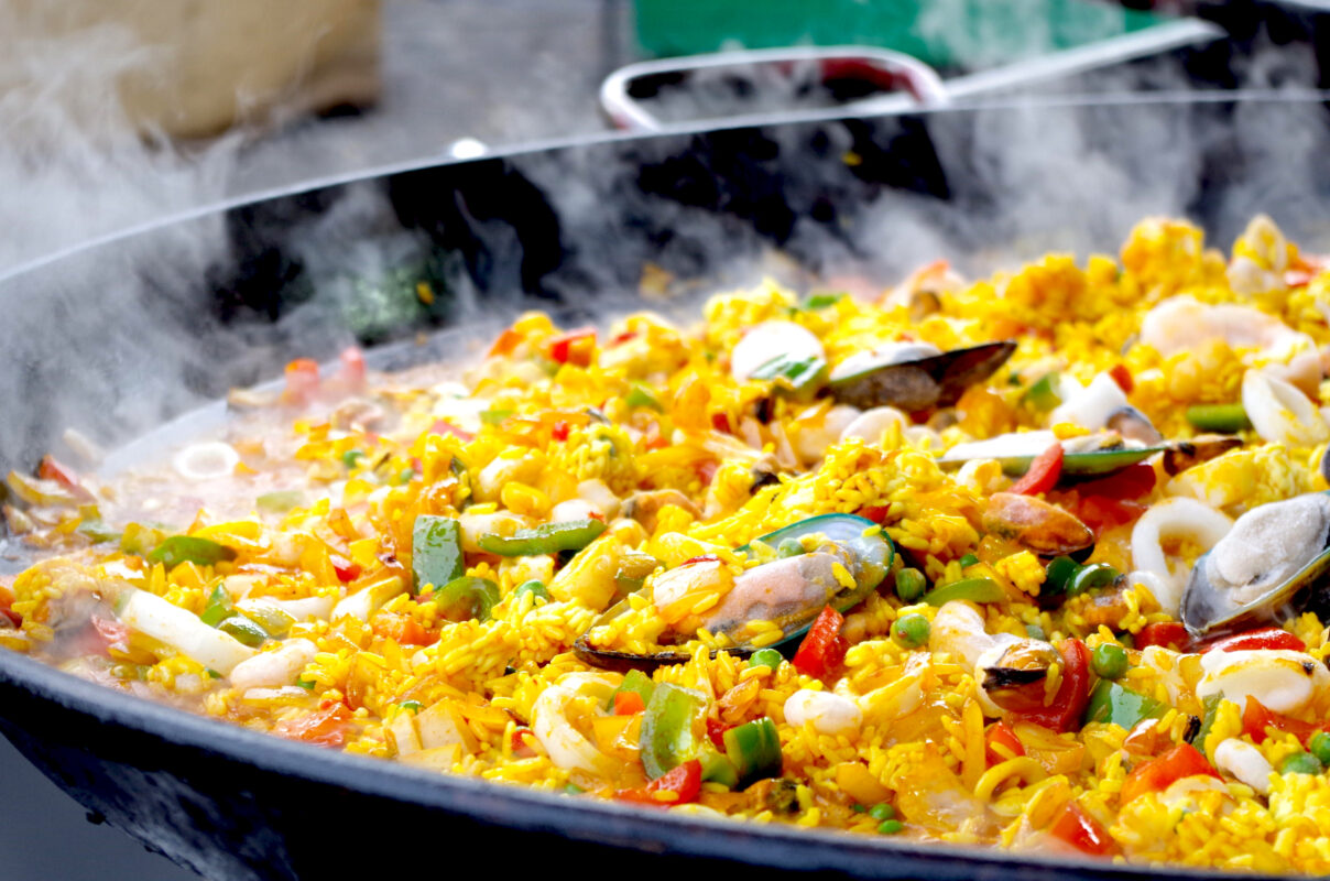 Two large-format PSRT paella pans cooking live at a 100-person Bay Area event