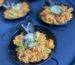 Individual servings of Spanish paella in traditional steel pans at a PSRT Bay Area holiday event